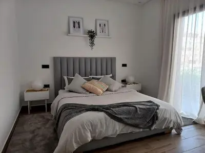a white bedroom with a large bed and a window at Appartement cosy au cœur de Marrakech avec piscine in Marrakech