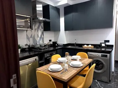 a kitchen with a table with yellow chairs and a kitchen with a stove at Appartement cosy au cœur de Marrakech avec piscine in Marrakech
