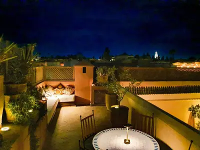 a patio with a table on a balcony at night at Riad 92 - Architect's Riad in the Exclusive Dar El Bacha in Marrakech