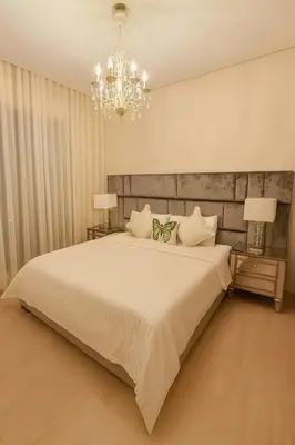 a bedroom with a large white bed and a chandelier at Appartement de luxe prestigia Golf Resort in Marrakech