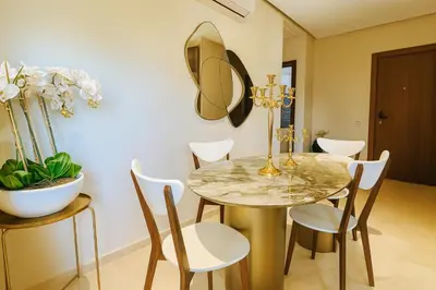 a dining room with a table and chairs and a mirror at Appartement de luxe prestigia Golf Resort in Marrakech