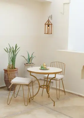a table and chairs in a room with plants at Riad Rahal in Marrakech
