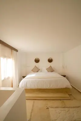 a white bedroom with a bed and a window at Riad Rahal in Marrakech