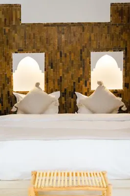 a room with two beds with pillows and a bench at Riad Rahal in Marrakech