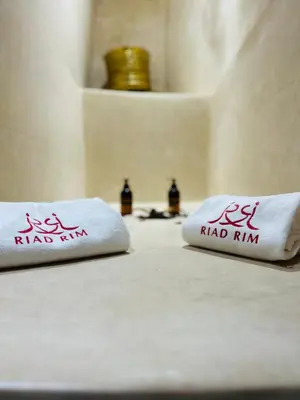 two white towels with red writing on a bed at Riad RIM in Marrakech