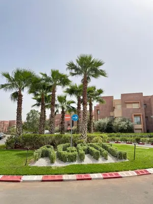 a park with palm trees and bushes in front of a building at Oasi Marrakech in Marrakech
