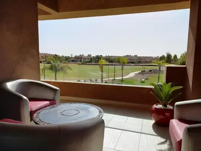 a room with a table and chairs and a large window at Corail Apart Golfique -Prestigia in Marrakech