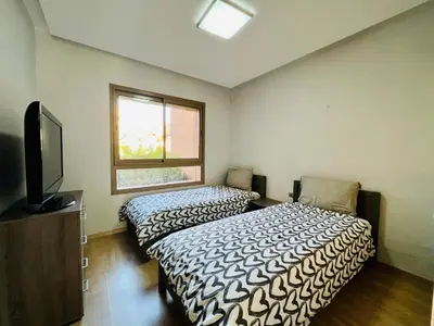 a bedroom with two beds and a tv and a window at Corail Apart Golfique -Prestigia in Marrakech