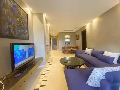 a living room with a blue couch and a tv at Corail Apart Golfique -Prestigia in Marrakech