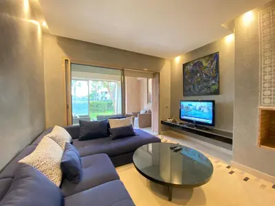 a living room with a blue couch and a tv at Corail Apart Golfique -Prestigia in Marrakech