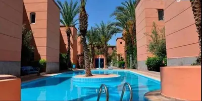 a swimming pool with palm trees in a resort at Le Havre de paix in Marrakech