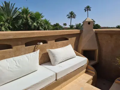 a white couch on a balcony with palm trees at Le Havre de paix in Marrakech
