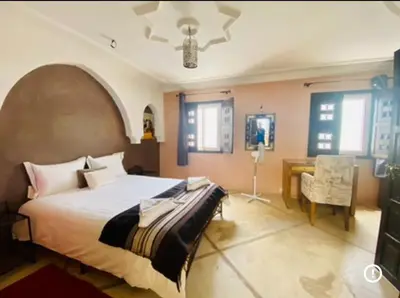 a bedroom with a large bed and a desk in it at Le Havre de paix in Marrakech