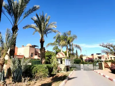 a driveway with palm trees in front of a house at Appart atlas resort in Marrakech