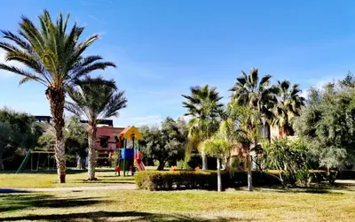 a park with palm trees and a playground at Appart atlas resort in Marrakech