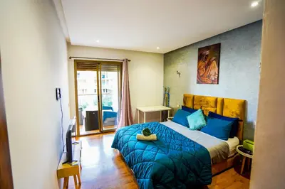 a bedroom with a bed with blue pillows and a television at Apartment pool marrakech in Marrakech