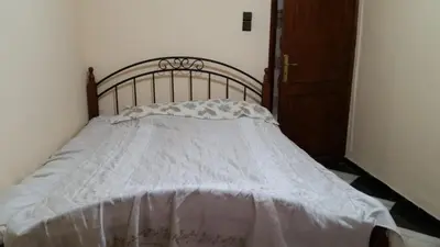 a bed with a white comforter on it at Samsat Apartement House Marakech in Marrakech