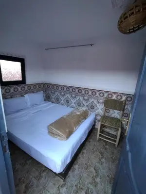 a bedroom with a white bed and a chair at Kesh apartment in Marrakech