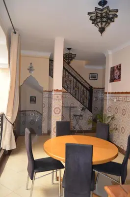 a dining room with a wooden table and chairs at JHDARINNA in Marrakech
