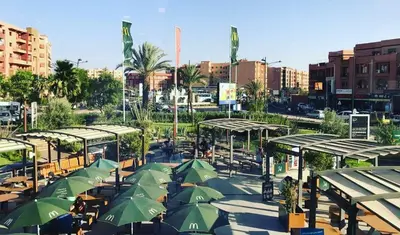 a group of tables with green umbrellas in a city at Royal Deluxe Diamond - Marrakech, Luxe Pool View in Marrakech