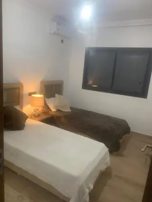 a bedroom with two beds and a flat screen tv at Family apart in Marrakech