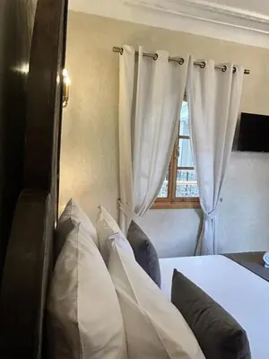 a bedroom with a bed with white pillows and a window at Riad Al Nubala in Marrakech