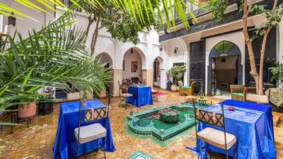 a courtyard with tables and chairs and palm trees at Riad ABBASSIA Marrakech Premiere - Authentic Medina Experience in Marrakech