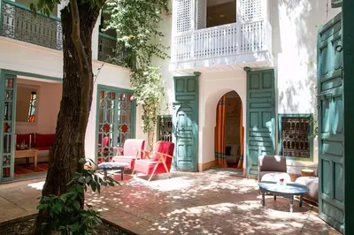 a courtyard with chairs and a table and a tree at Riad Dar Zitouna Marrakesh - entire house in exclusivity in Marrakech