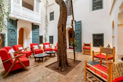 a courtyard with red chairs and a tree at Riad Dar Zitouna Marrakesh - entire house in exclusivity in Marrakech