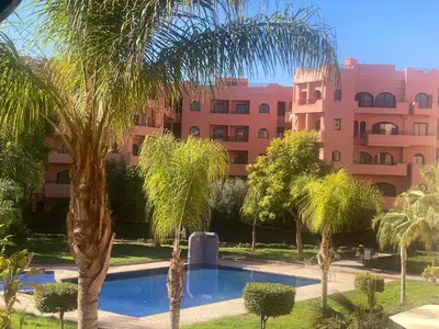 a resort with a palm tree and a building at un moderne chic appartement vue sur piscine in Marrakech