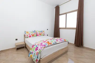 a bedroom with a bed with colorful sheets and a window at lafamilia in Marrakech