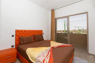 a bedroom with an orange bed and a large window at lafamilia in Marrakech