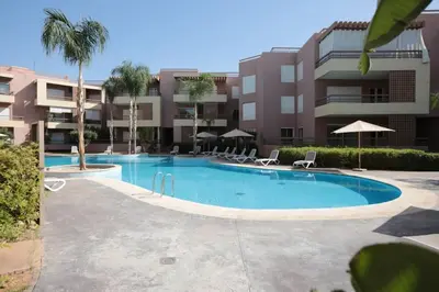 a swimming pool with chairs and a building at APPARTEMENT RIAD WHITE GOLDEN in Marrakech