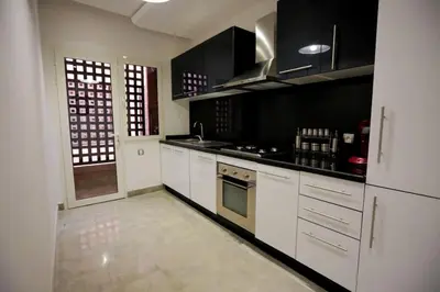 a kitchen with white cabinets and black appliances at APPARTEMENT RIAD WHITE GOLDEN in Marrakech