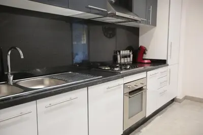 a kitchen with white cabinets and a sink and a stove at APPARTEMENT RIAD WHITE GOLDEN in Marrakech