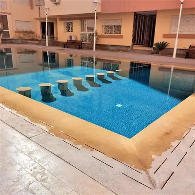 an empty pool with tables and chairs in a building at Appartement pour Familles en Résidence-Piscine et WiFi Fibre Optique in Marrakech