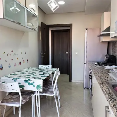 a kitchen with a table and chairs in a room at Appartement pour Familles en Résidence-Piscine et WiFi Fibre Optique in Marrakech