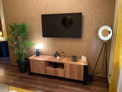 a living room with a wooden table with a tv on the wall at Appartment Zaina in Marrakech