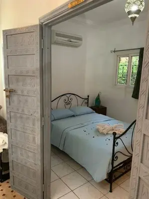 a bedroom with a bed and a door leading into a room at Ryad de charme authentique piscine calme in Marrakech