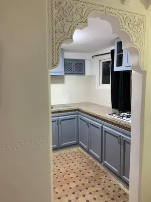 a kitchen with blue cabinets and a tile floor at Ryad de charme authentique piscine calme in Marrakech