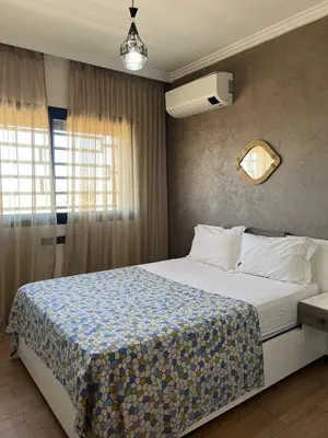 a bedroom with a large bed in a room with a window at Appartement avec piscine in Marrakech