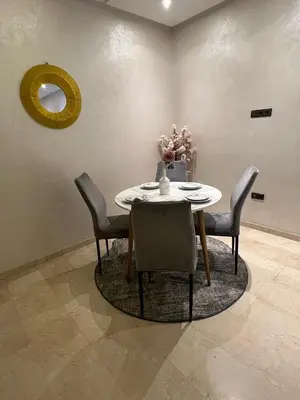 a dining room with a table and chairs and a mirror at Appartement avec piscine in Marrakech