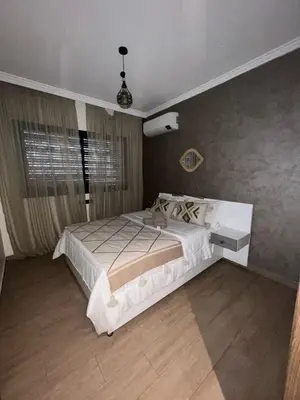 a bedroom with a large white bed and a window at Appartement avec piscine in Marrakech
