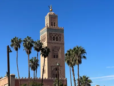 a clock tower with palm trees in the foreground at Riad Dar Les Freres in Marrakech
