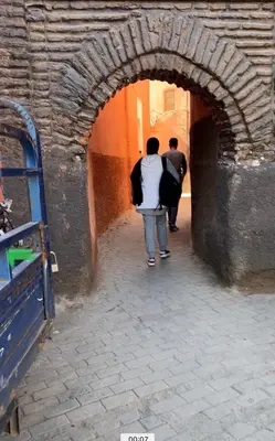 two people walking through an archway in a building at Riad Dar Les Freres in Marrakech