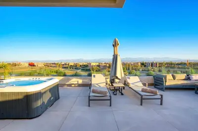 a patio with a hot tub and chairs and an umbrella at Villa Simeon Marrakech in Marrakech