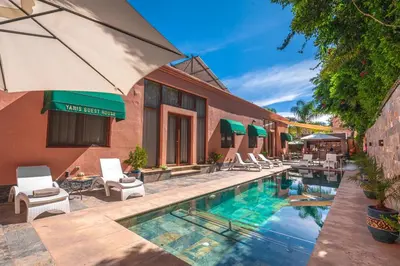an outdoor swimming pool with chairs and an umbrella at Yanis Guest House in Marrakech