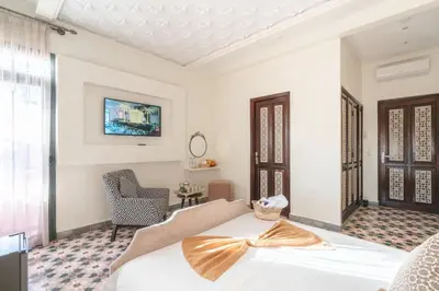 a bedroom with a white bed and a chair at Yanis Guest House in Marrakech