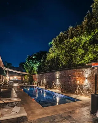 a swimming pool at night with a stone wall at Yanis Guest House in Marrakech