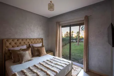 a bedroom with a bed and a sliding glass door at Prestigia golf city porte agate in Marrakech